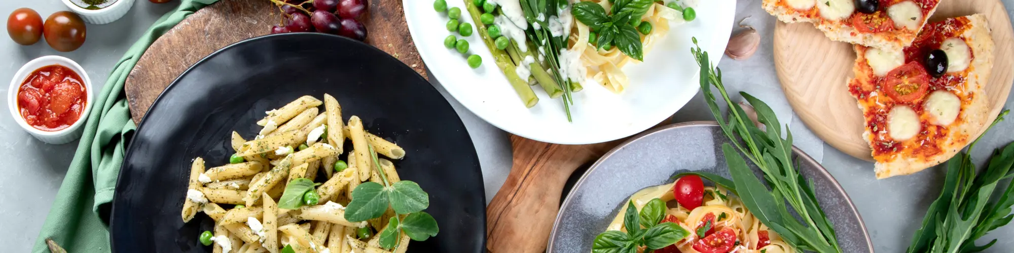 Läskande matbord fotat ovanifrån med pasta, pizza och goda tomatsåser