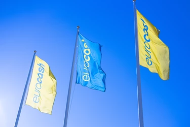 Eurocash-flaggor som vajar i vinden mot en blå himmel.