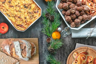 Läskande matbord fotat ovanifrån med julmat, köttbullar, janssons frestelse, bröd och lussebullar