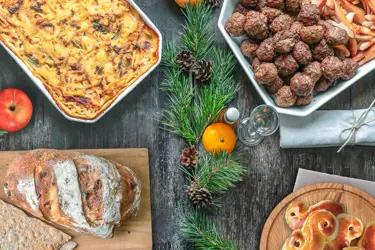 Läskande matbord fotat ovanifrån med julmat, köttbullar, janssons frestelse, bröd och lussebullar