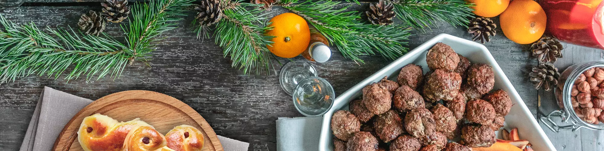 Läskande matbord fotat ovanifrån med julmat, köttbullar, janssons frestelse, bröd och lussebullar