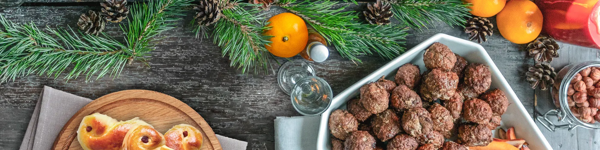 Läskande matbord fotat ovanifrån med julmat, köttbullar, janssons frestelse, bröd och lussebullar
